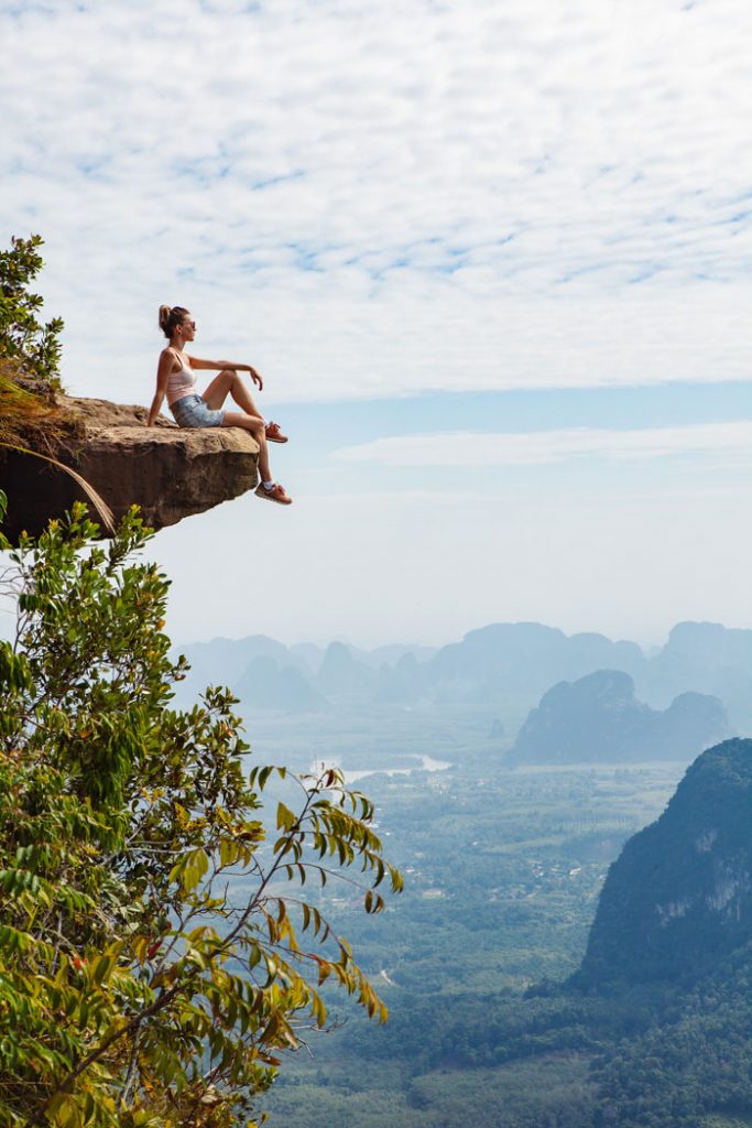 woman sitting on edge of the mountain