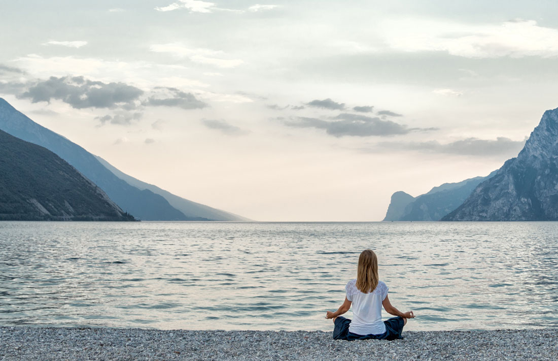 woman meditating facing the ocean
